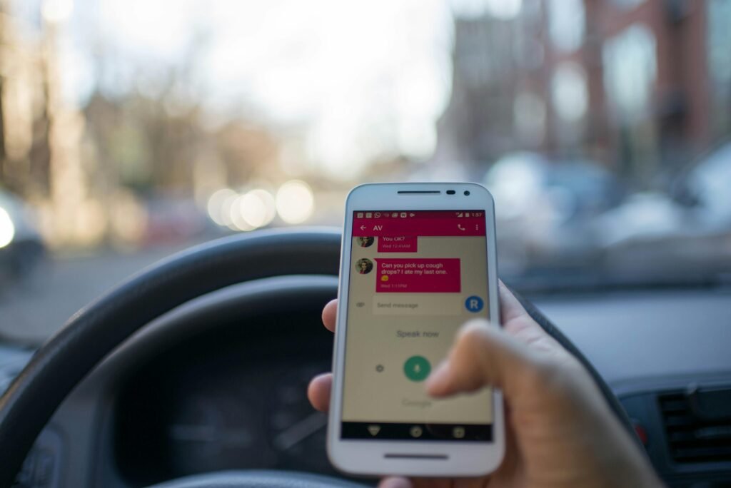 A person texting on a smartphone while driving an automobile in a city, illustrating distracted driving and technology use.