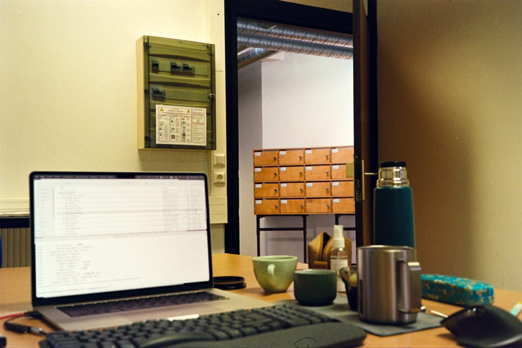 A cozy office workspace featuring a laptop, mugs, and storage drawers in a warm setting.